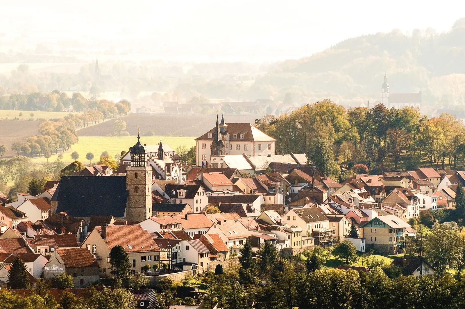 Blick über die Altstadt von Geisa im Morgenlicht, mit Schloss, Kirchturm und den Hügeln der Rhön im Hintergrund