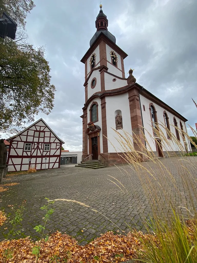 Die Pfarrkirche in Eiterfeld mit dem Fachwerkhaus davor im Herbst